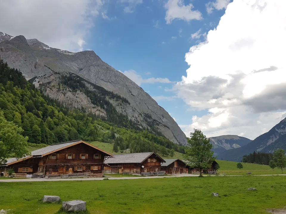 Almhütten vor einer Felswand im Hochtal