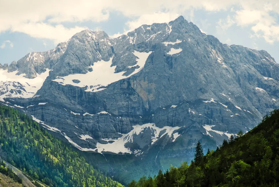 Schneebedecktes Bergmassiv über einem bewaldeten Tal